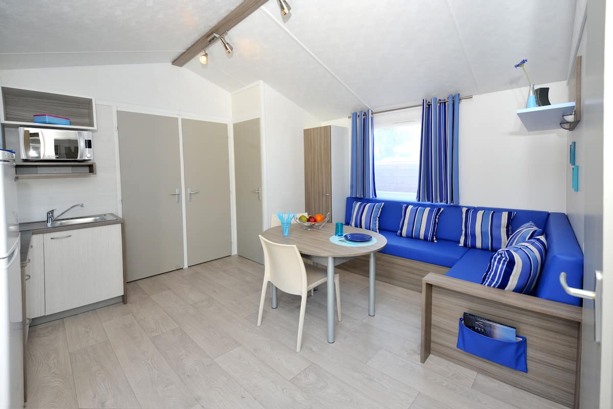 A compact living space with a kitchenette, a dining table, a sofa, and a small storage unit.