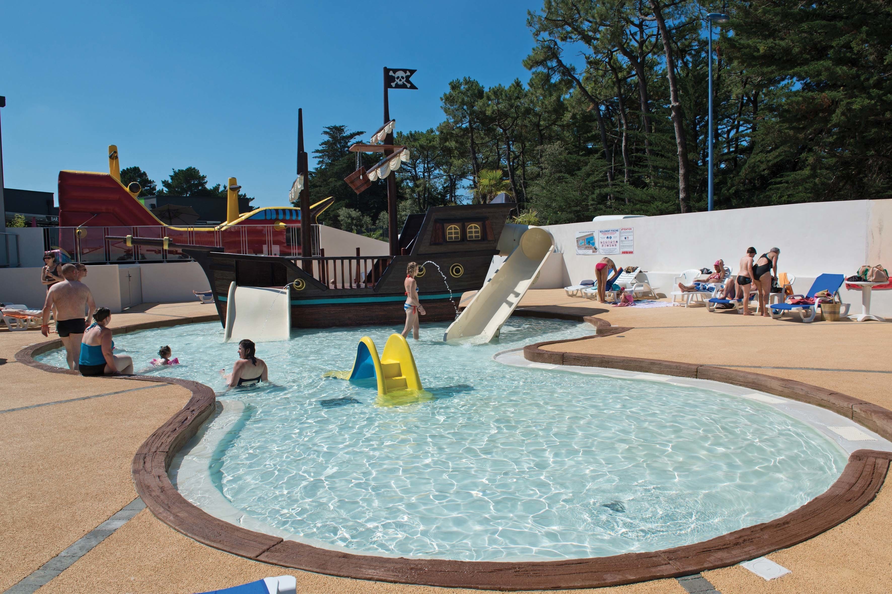 A swimming pool area with slides and a pirate-themed play structure.