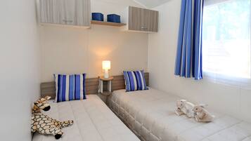 A bedroom with two beds, a nightstand, a lamp, and stuffed animals.