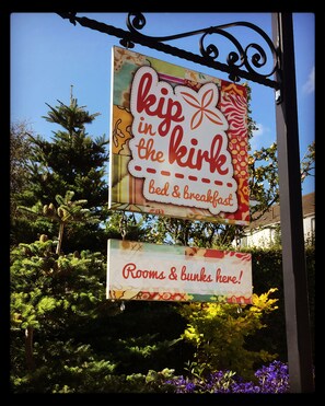 A sign for 'kip in the kirk' offering bed & breakfast and rooms & bunk beds.