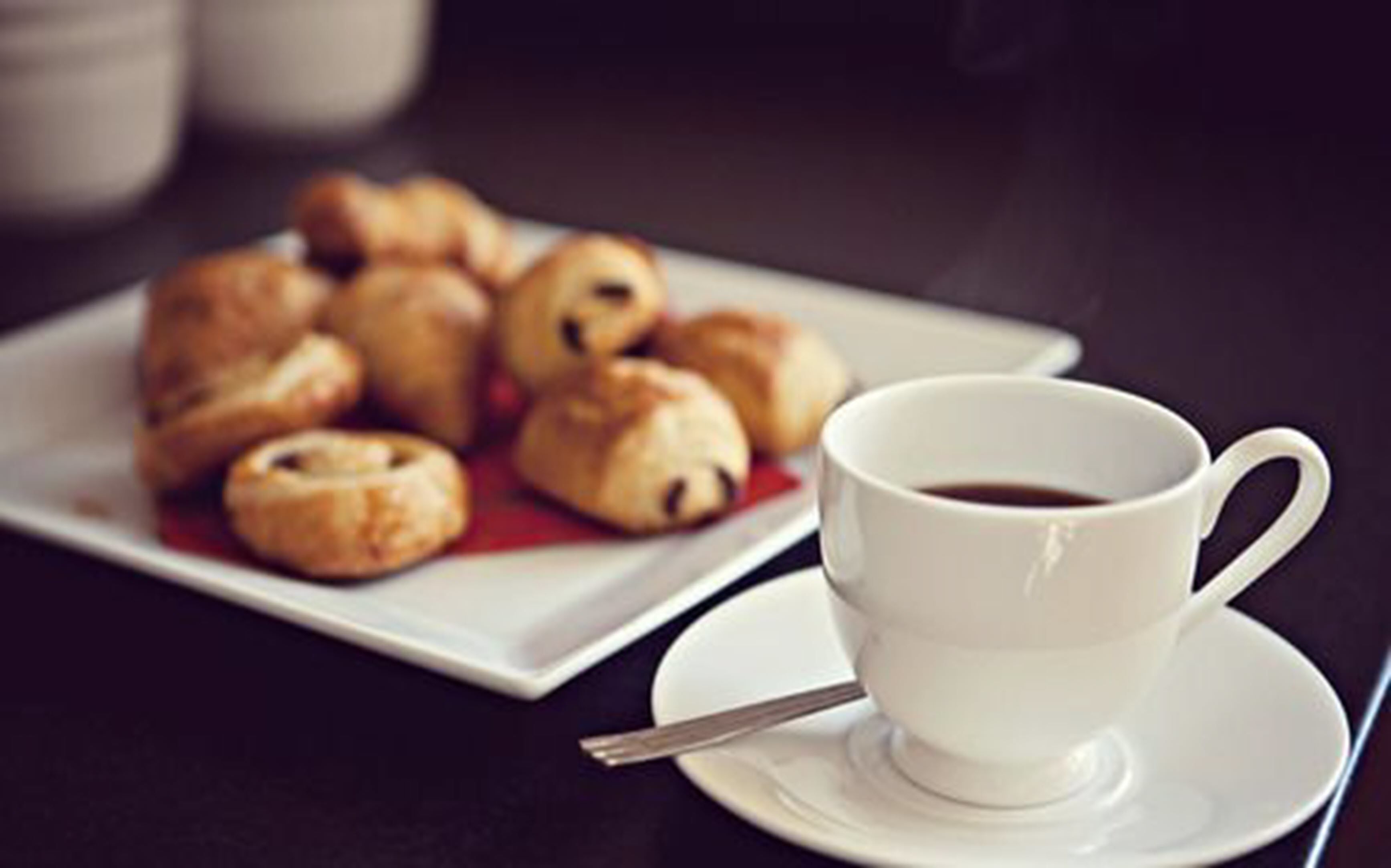 Un plato de pasteles y una taza de café sobre una mesa.
