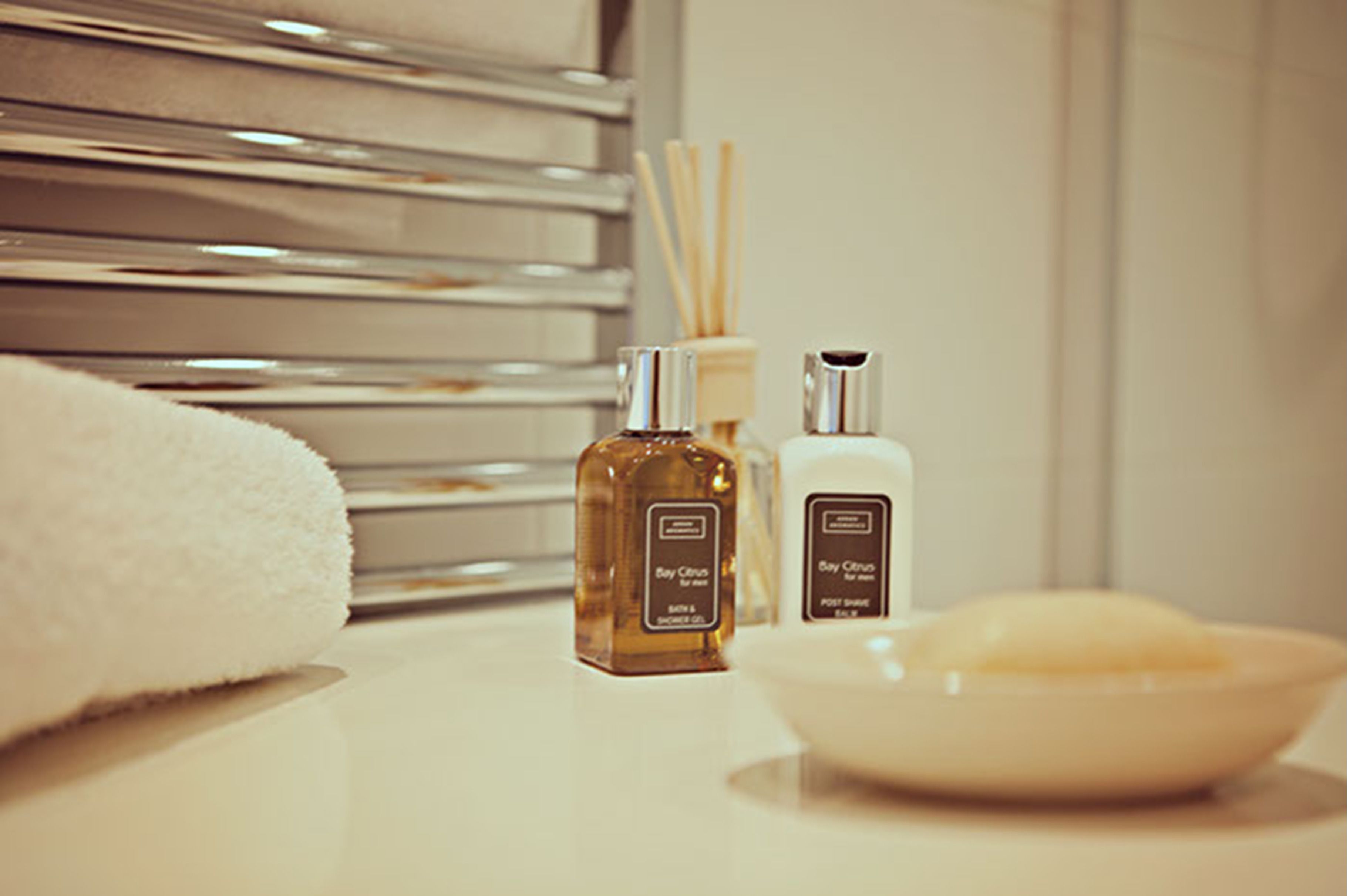 Casa de banho com toalha branca, dois frascos de gel de banho Bay Citrus e um sabonete em barra.