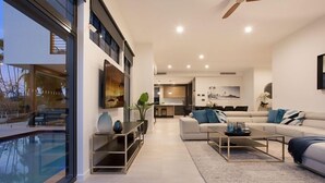Ein modernes Wohnzimmer mit Pool, einer Sofagarnitur und einem Essbereich.