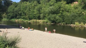 Una zona al costat del riu amb gent fent diverses activitats a prop de l'aigua.