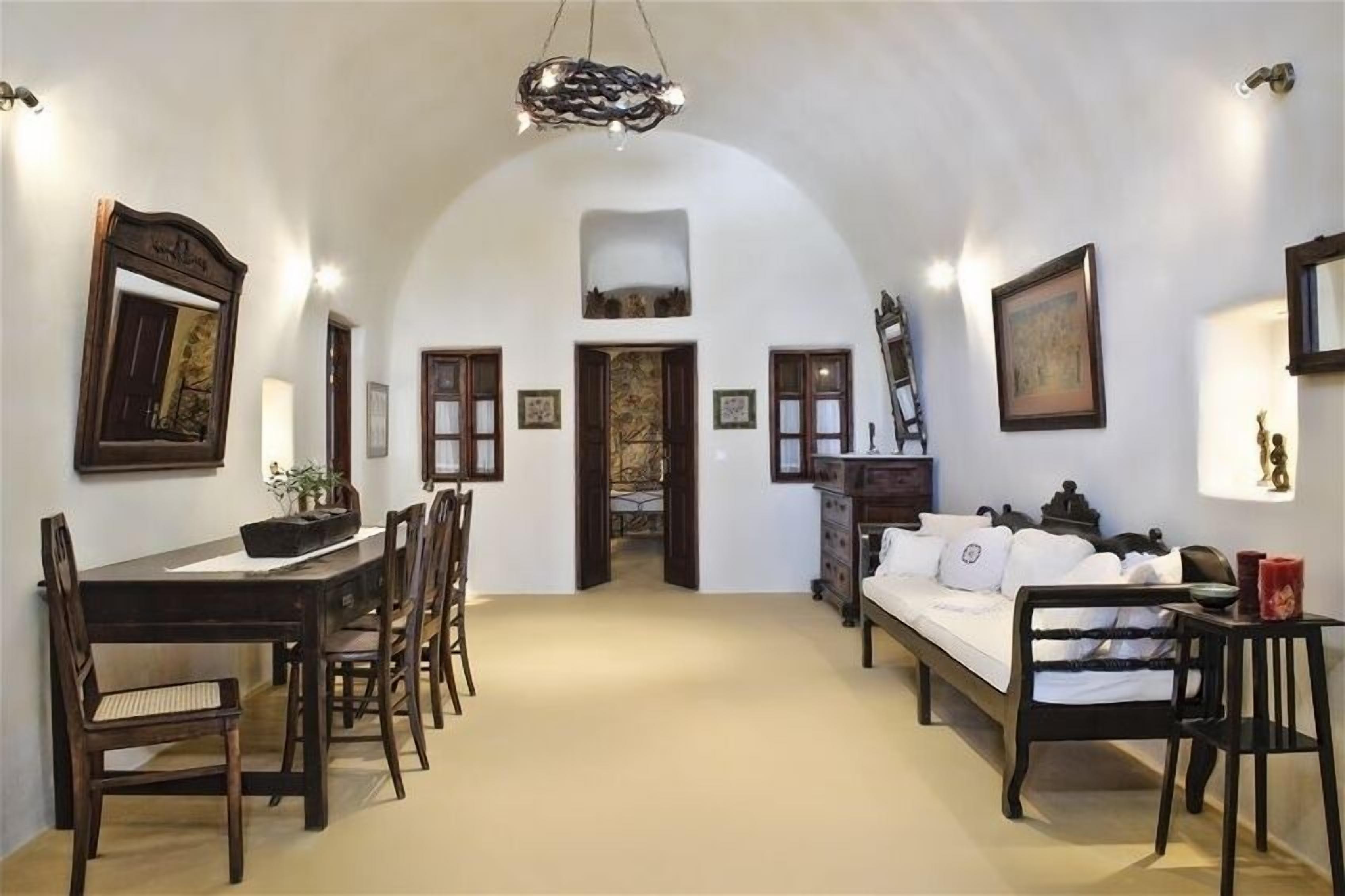 A room with a dining table, chairs, a bed, and a staircase leading to an upper level.