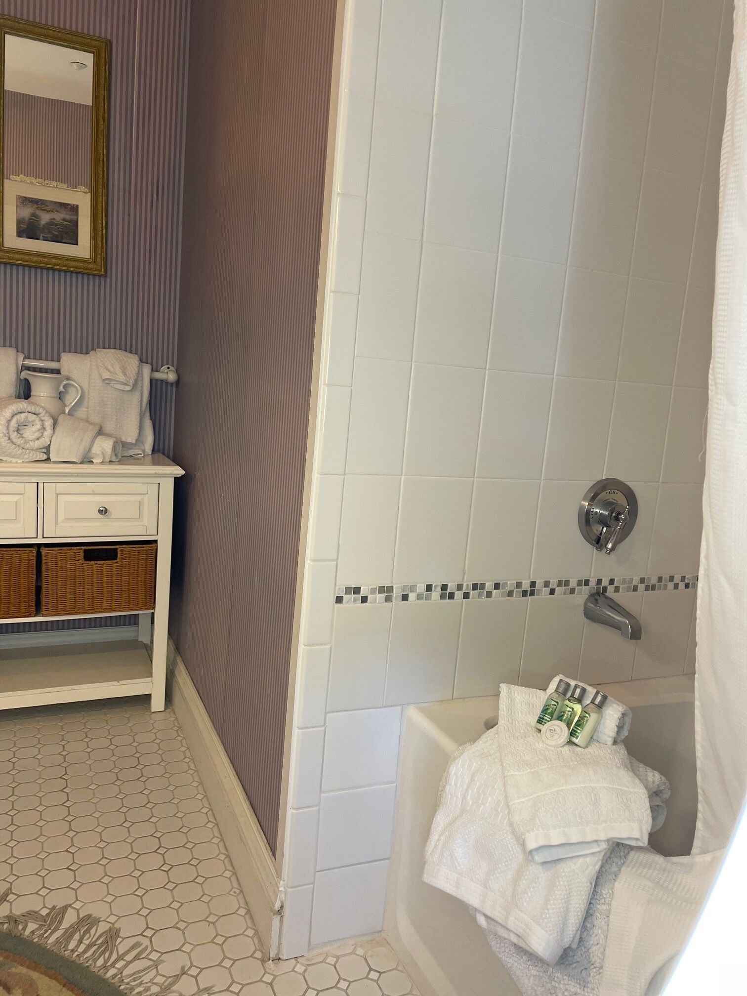 Un baño con tocador blanco, espejo, toallero y zona de ducha.