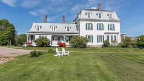 A large, two-story white house with green shutters, a front porch, and a well-maintained lawn. - Langworthy Inn (Westerly)