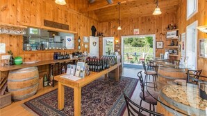 A wooden interior with a bar area, wine bottles, and a view of the outdoors. - Langworthy Inn (Westerly)