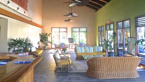 A spacious lobby with a high ceiling, ceiling fans, a reception desk, seating area with chairs and a sofa, and large windows allowing natural light. - OCEANFRONT 3+2.5 AC Pickleball Onsite! Walk to Keauhou Bay & Kahaluu Beach Park (Kailua-Kona)