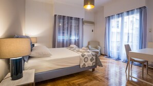 Een hotelkamer met een bed, een bureau, een stoel, een lamp en een raam met gordijnen.