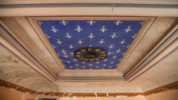 Een kamer met een plafond waarop een klok en decoratieve patronen staan afgebeeld.
