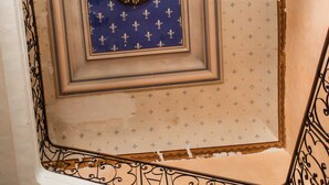 A staircase with ornate metal railings and a decorative ceiling with a clock. - Furnished with charm in the Drôme Provençale (La Bégude-de-Mazenc)