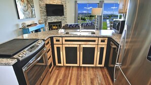 A modern kitchen with a large island, built-in oven, and stainless steel appliances.