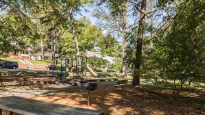 Ein Park mit Picknicktischen, Spielgeräten und Bäumen.
