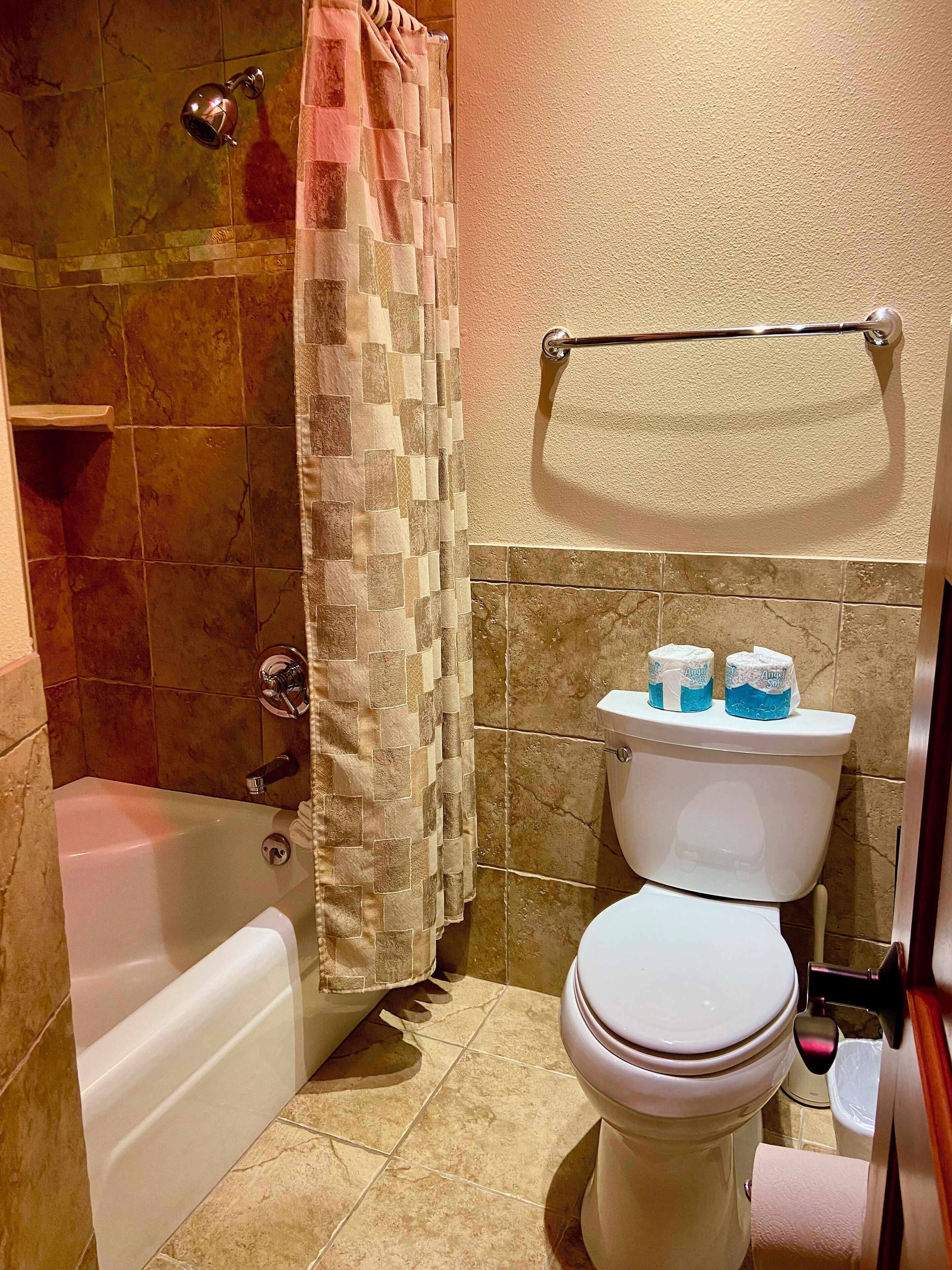 A bathroom with a bathtub, toilet, and shower curtain.