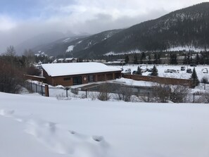 Ein Gebäude mit schneebedecktem Dach, einem Parkplatz und einem Bergpanorama im Hintergrund.