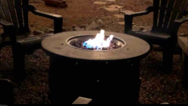 Ein Außenbereich mit Sitzgelegenheit, einem Feuerkorb, zwei Stühlen und einer Holzterrasse.