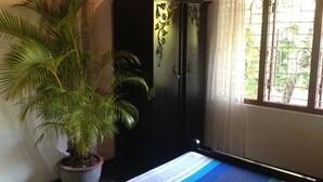 Une chambre avec un lit, une plante en pot, une armoire et une fenêtre donnant sur un paysage verdoyant.