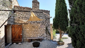 A stone building with a wooden door, a bench, and a hanging cloth. - Provencal farmhouse in central Provence (Caumont-Sur-Durance)