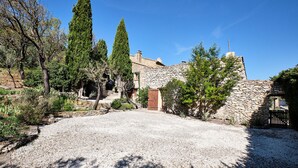 A stone building with a gravel driveway, surrounded by trees and vegetation. - Provencal farmhouse in central Provence (Caumont-Sur-Durance)