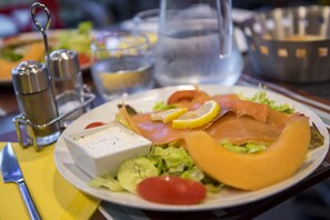 Een bord met zalm, citroen en salade.