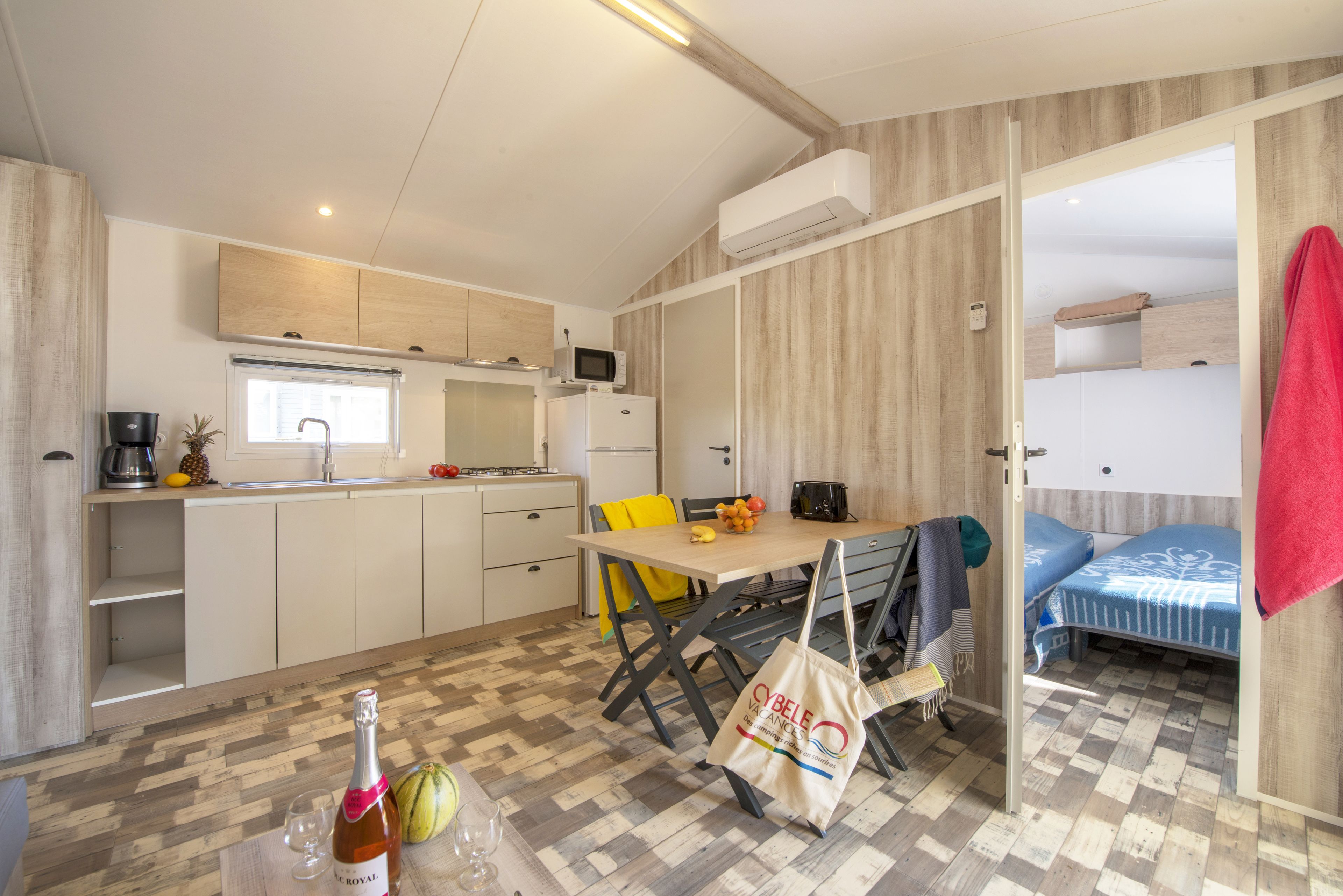 Een compacte keuken met een eethoek, een magnetron en een bed met een blauwe spreideel.