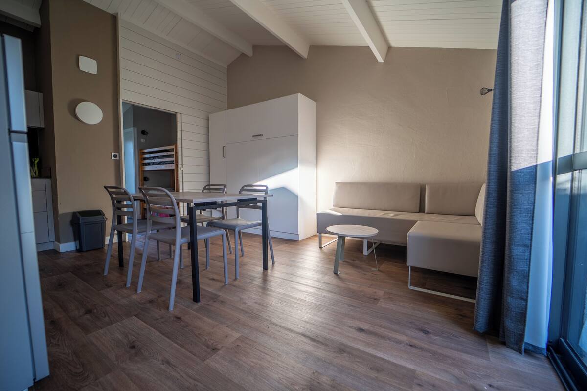 Un salon moderne comprenant un coin repas, un plancher en bois, un canapé et une petite table ronde.