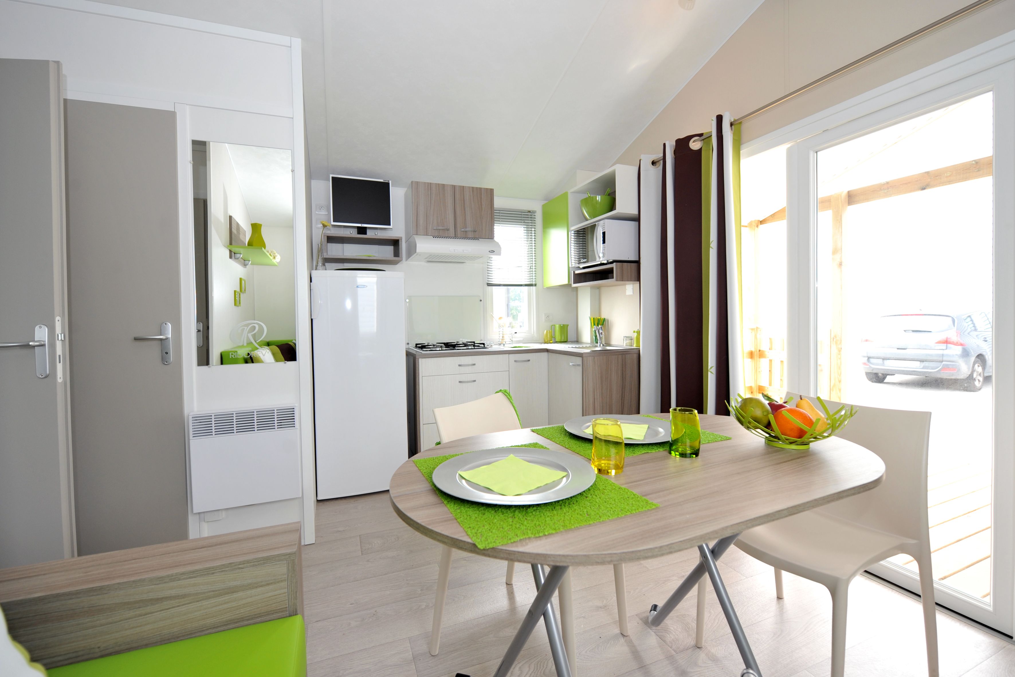 Una cocina moderna con armarios blancos, un microondas y una zona de comedor con una mesa dispuesta para dos.