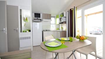 Una cocina moderna con armarios blancos, un microondas y una zona de comedor con una mesa dispuesta para dos.