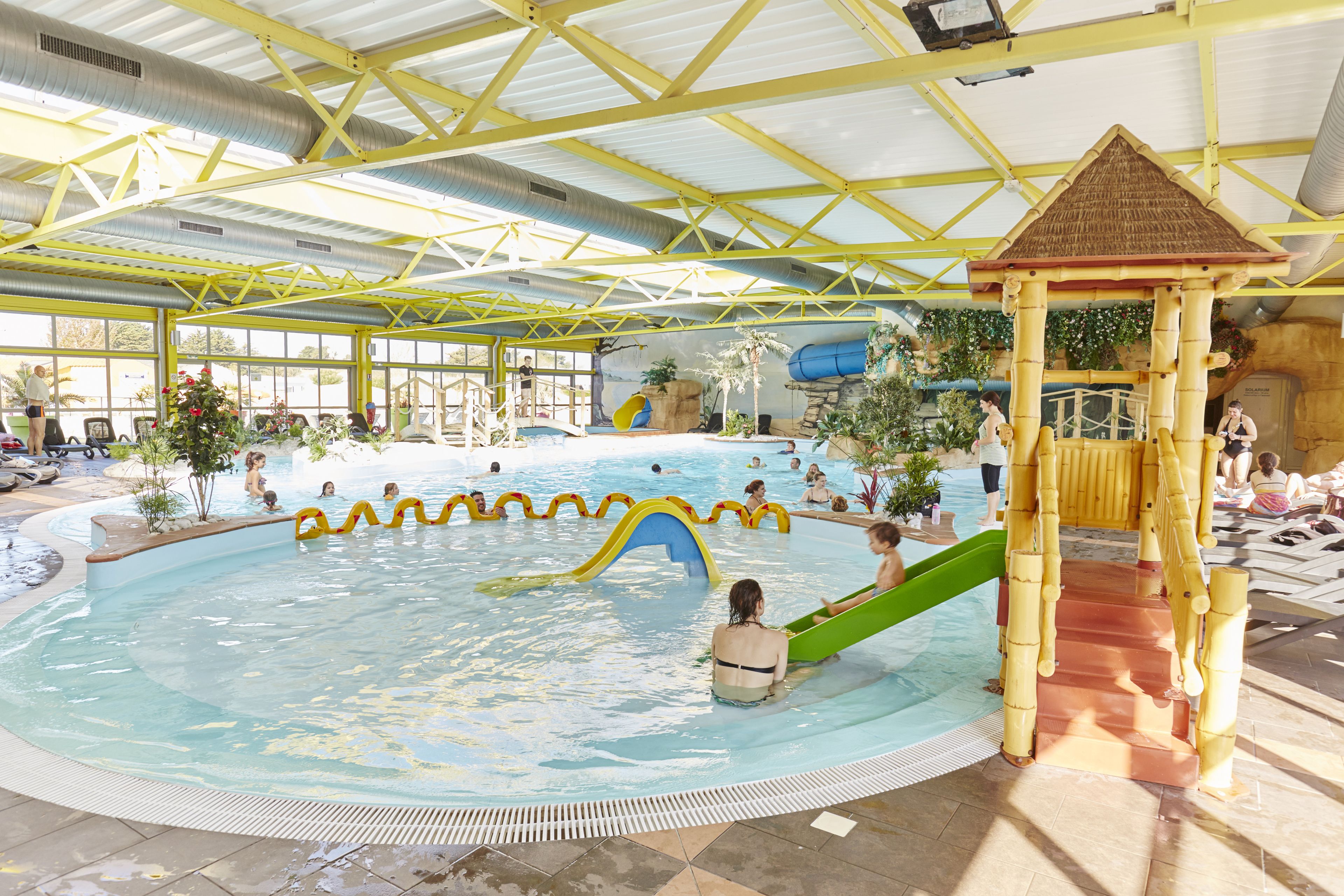 An indoor swimming pool with slides and a play area.