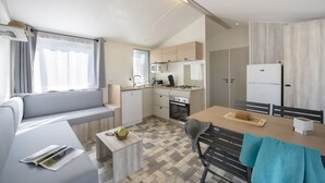 Een kleine keuken met een kookplaat, magnetron en koelkast.