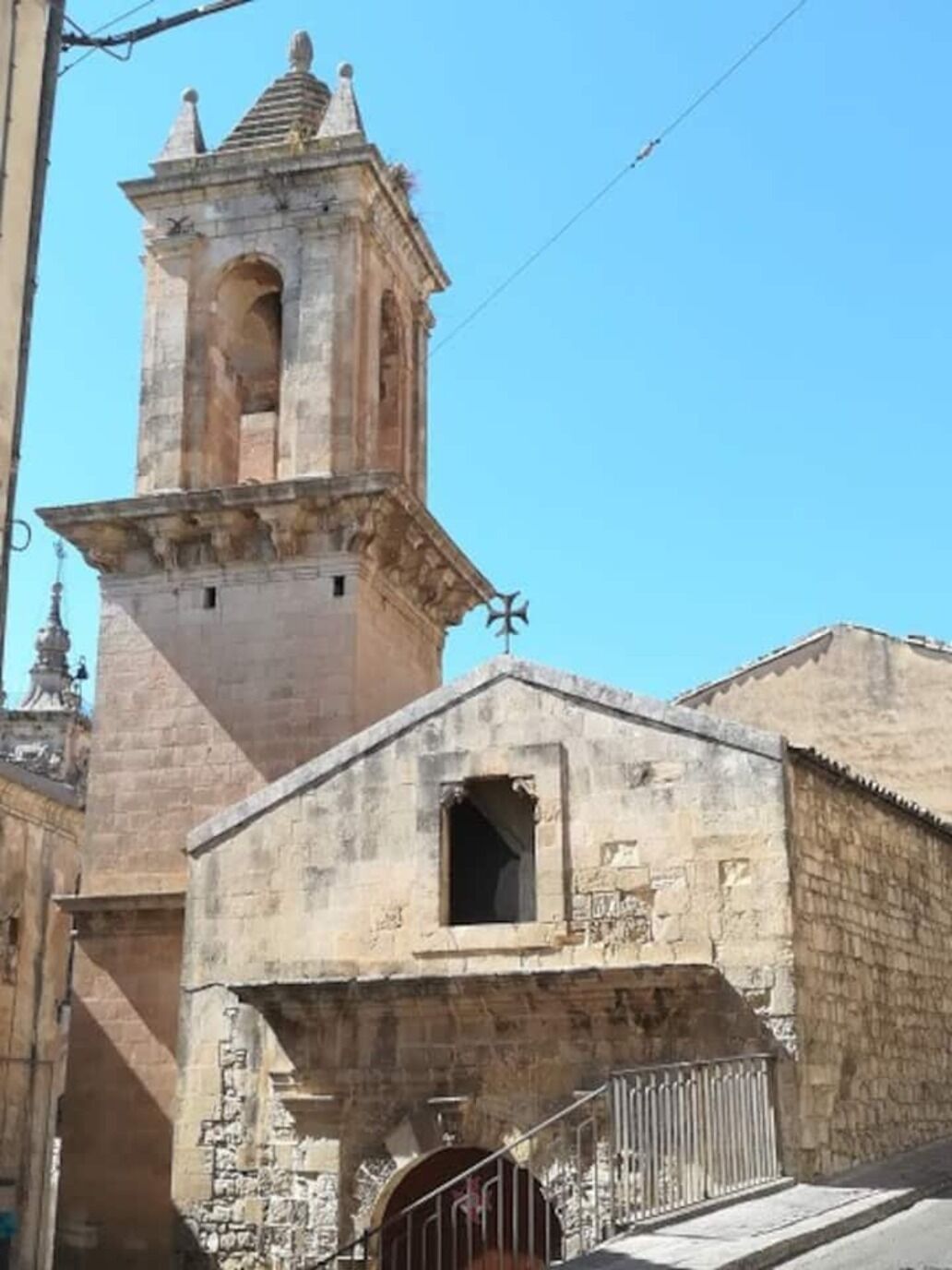 A historic stone building with a bell tower and a small entrance gate.
