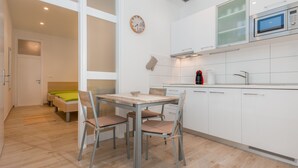 A modern kitchen with white cabinets, a microwave, and a clock on the wall.