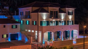 A multi-story house with a balcony, a garage, and a well-lit entrance.