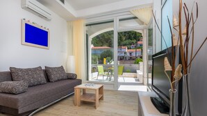 A modern living room with a sofa, a coffee table, a flat-screen TV, and a view of the outside.