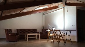 Et værelse med træloft, en brun lædersofa, et træbord og en stol med en hvid lampe.