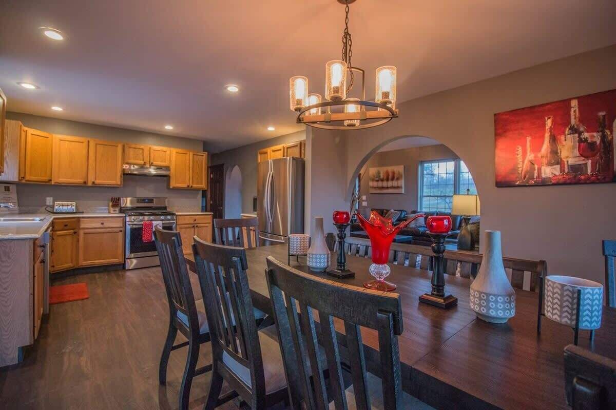 A modern kitchen with wooden cabinets, stainless steel appliances, and a dining area with a chandelier.