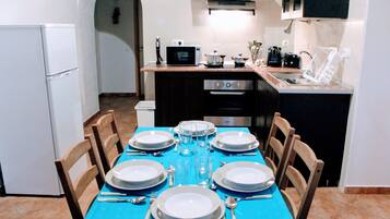 A dining area with a blue tablecloth, white plates, and silverware set for six.