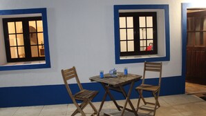 Una habitación con dos ventanas, una mesa de madera y dos sillas de madera.