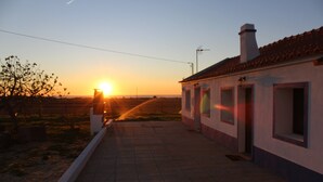 Un camino que lleva a un edificio con techo de tejas y una chimenea.