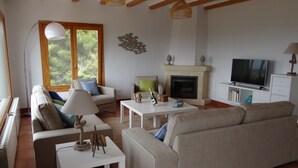Ein Wohnzimmer mit Kamin, Sofa, Couchtisch und Fernseher.