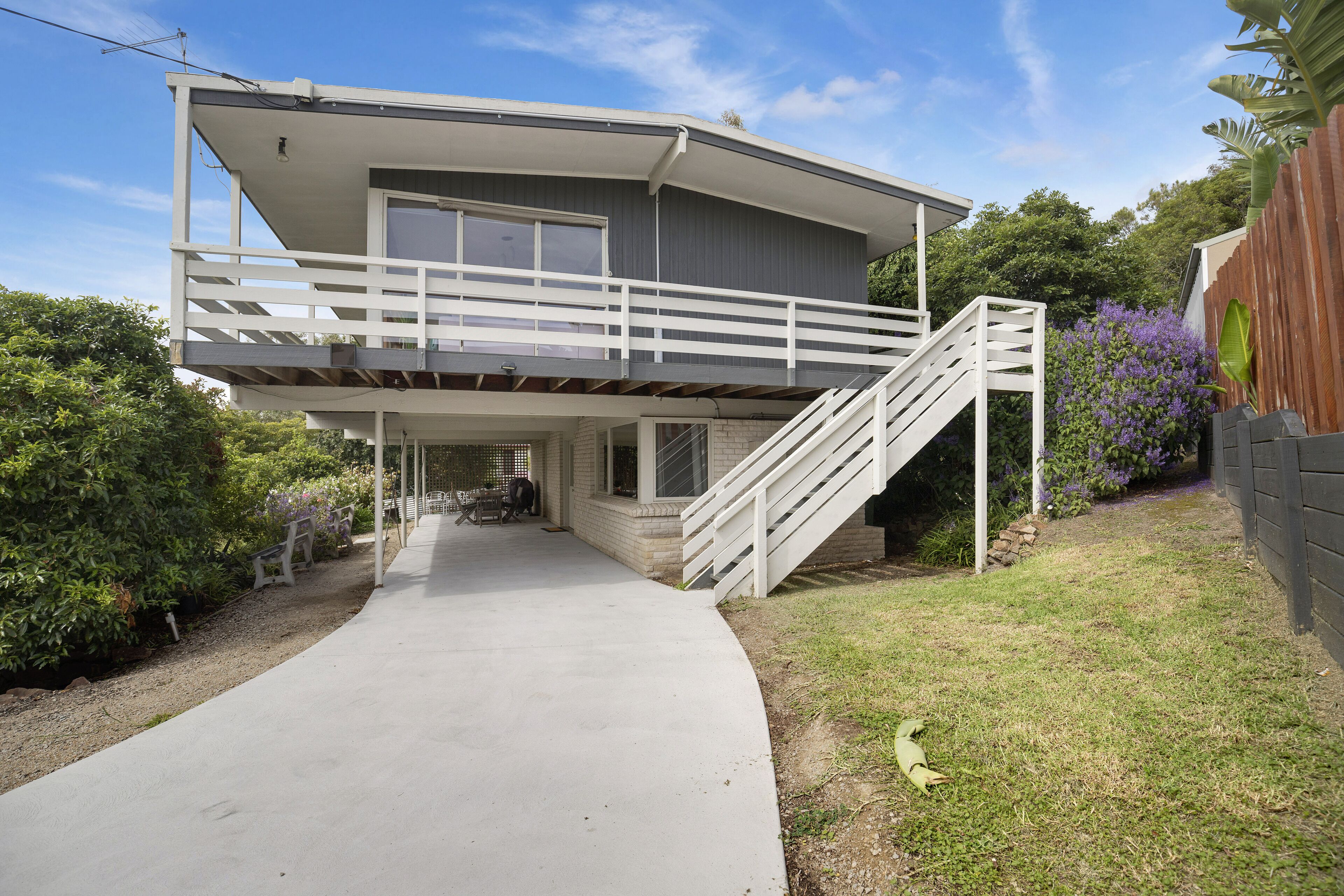 A two-story house with a covered front porch, a staircase to the upper level, and a driveway leading to the entrance.