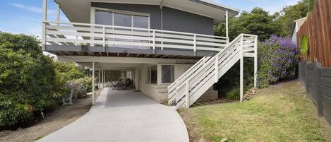A two-story house with a covered front porch, a staircase to the upper level, and a driveway leading to the entrance.
