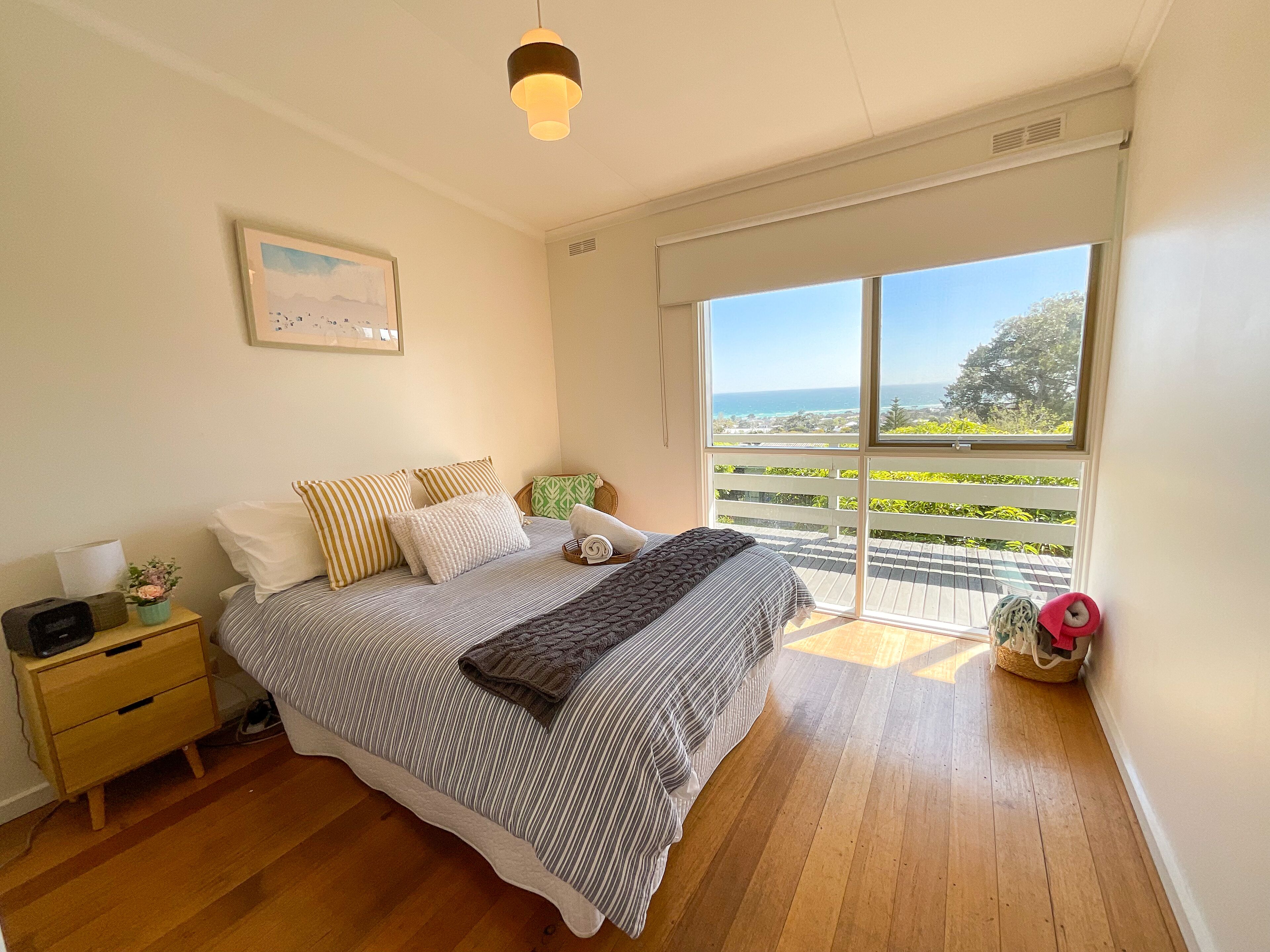 A bedroom with a bed, a nightstand, a window with a view of the outdoors, and a ceiling light.