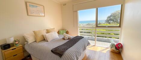A bedroom with a bed, a nightstand, a window with a view of the outdoors, and a ceiling light.