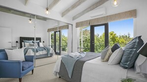 A modern bedroom with a large bed, a sofa, and a mirror. - Pet Friendly - Danny Boy Coastal Retreat in Rye (Rye)