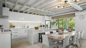 A modern kitchen with white cabinetry, a wooden island, and a dining area with a wooden table and white chairs. - Pet Friendly - Danny Boy Coastal Retreat in Rye (Rye)