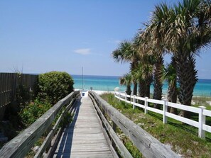 A wooden boardwalk leading to a beach with palm trees and a clear blue sky. - Private Pool, Walk to Beach 🏖️, Bright Sun Room, Quiet West End (Panama City Beach)