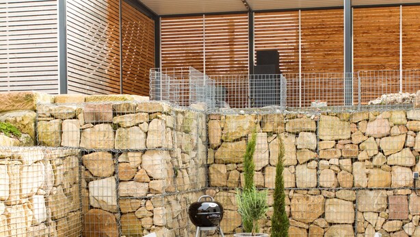 An outdoor patio with a stone wall, a covered seating area, and a grill. - Bed 'n Riesling - The vacation apartment in Forst a.d. Wine route with its own garden (Forst an der Weinstraße)