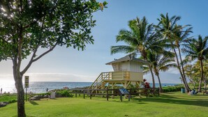 A lifeguard tower with a staircase, palm trees, and a view of the ocean. - KIHEI AKAHI CONDO STEPS FROM BEACH/GARDEN & PEEKABOO OCEAN VIEW/POOL-HOTEL ZONED (Kihei)